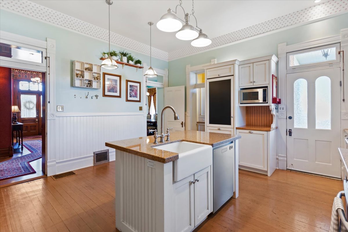 Kitchen featuring a central island with an apron-front sink, granite countertop, and beadboard paneling