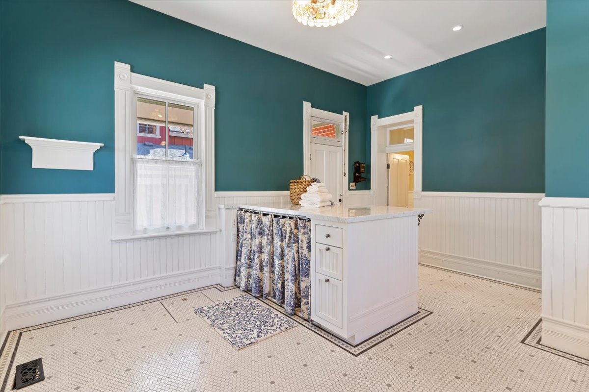 White wainscoting and teal walls complement the hexagon mosaic tile flooring