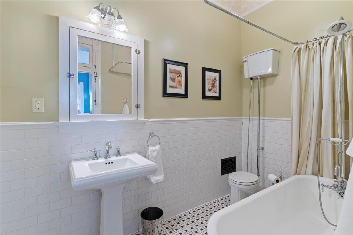 Classic bathroom featuring a pedestal sink, medicine cabinet with integrated lighting, and a clawfoot tub with a shower fixture