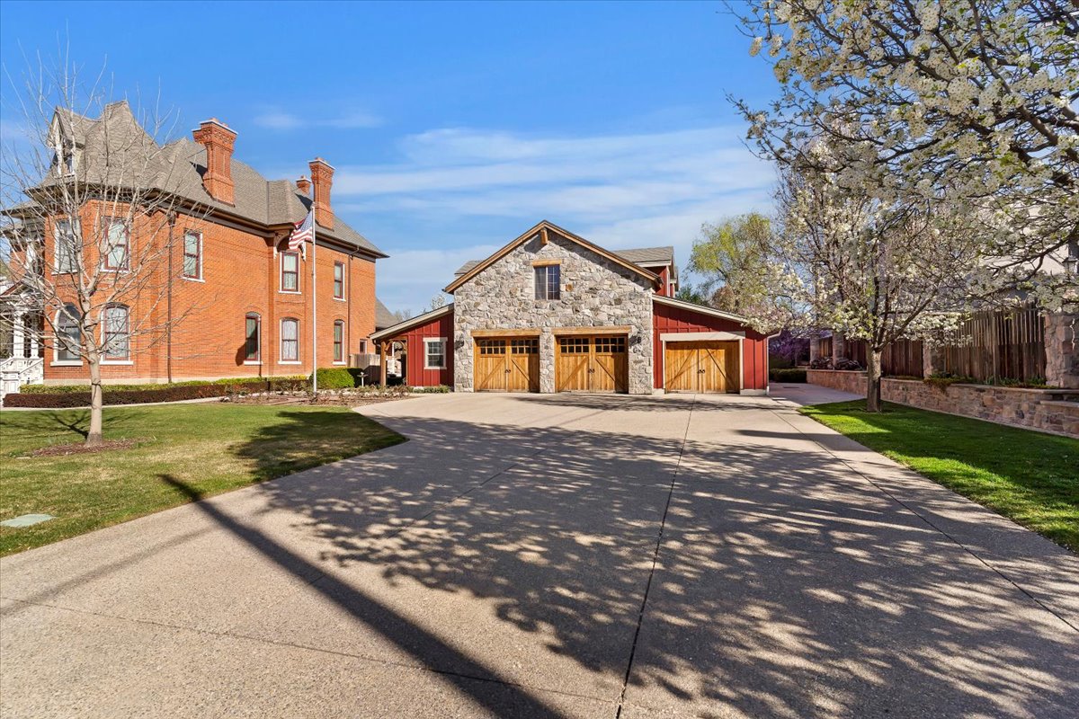 Expansive concrete driveway leading to a stone and wood-sided garage structure with multiple bay doors