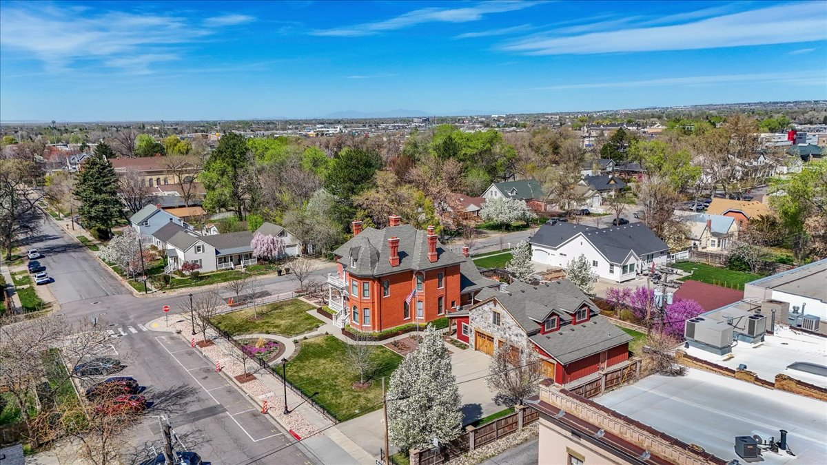 Historic red brick residence featuring multiple chimneys, a covered wrap-around porch, and a dormer window roofline