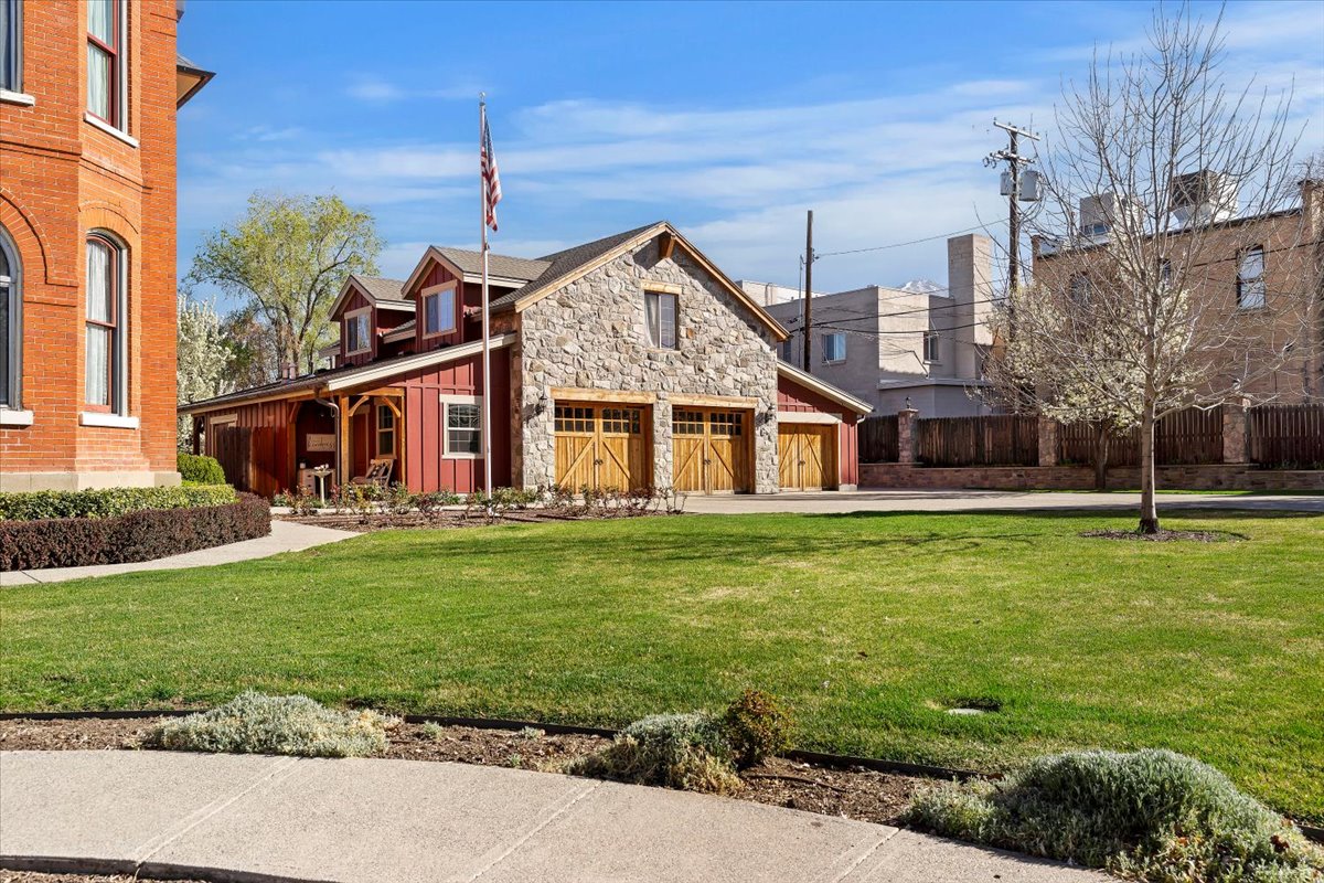 Stone and red siding structure featuring three wood-finish garage doors