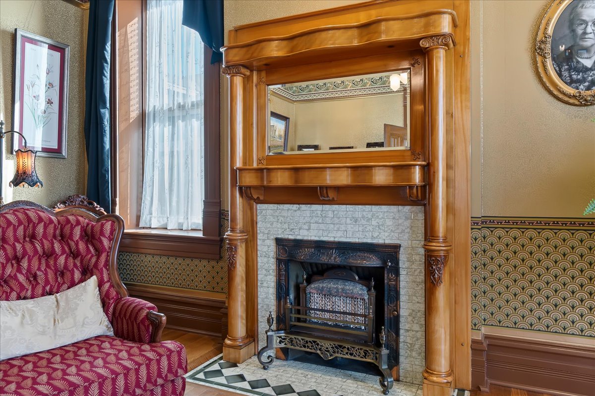 Ornate fireplace with a carved wood mantel, integrated mirror, and a cast-iron insert