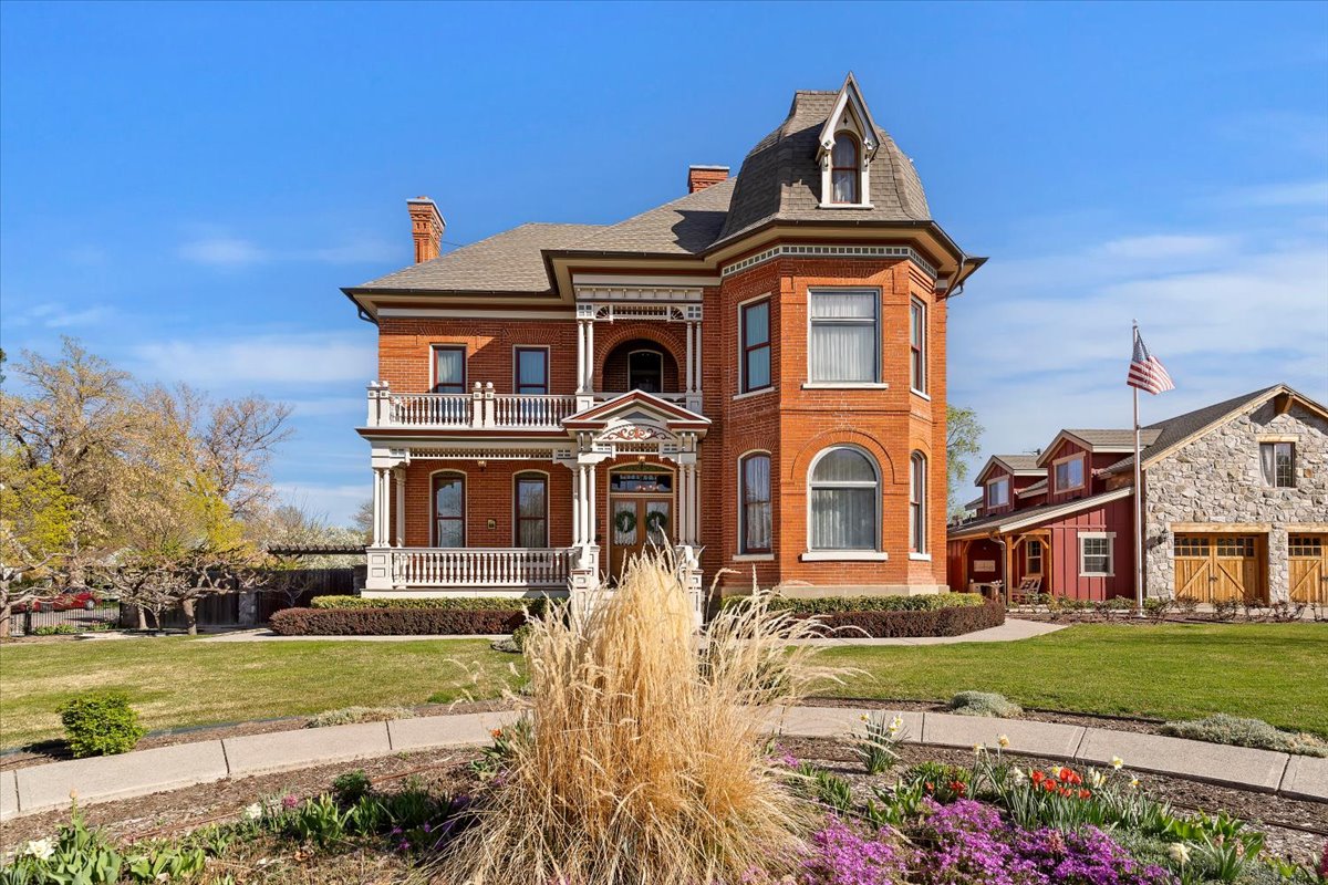 Brick exterior featuring a turret, multiple balconies with white railings, a covered porch, and arched windows