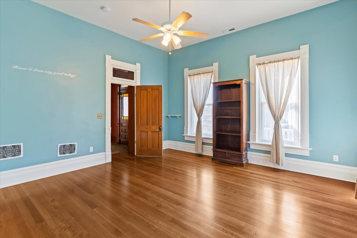 Hardwood flooring extends throughout this room, featuring light blue walls and prominent white baseboards