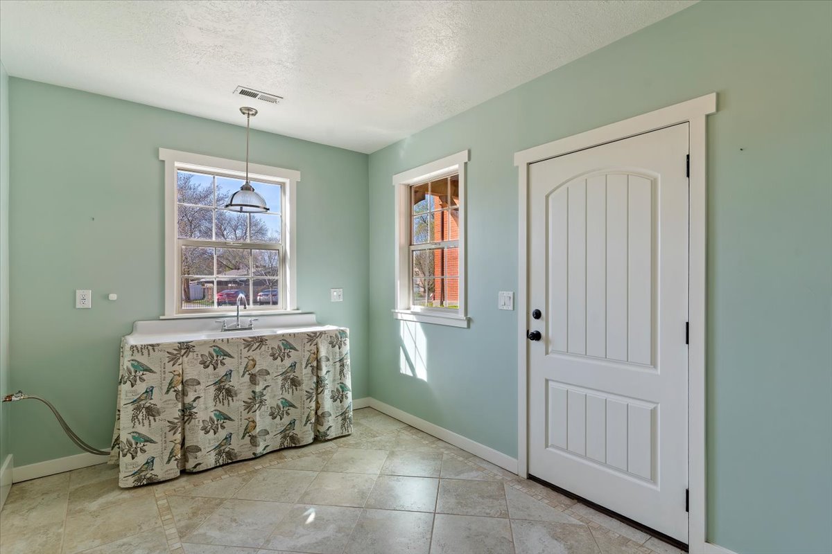 Light-filled room featuring two windows, a utility sink with countertop, and a paneled door with an arched top