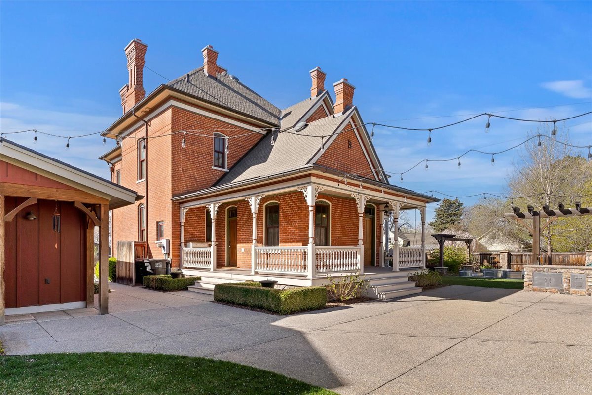 Historic brick exterior featuring a covered porch with decorative railings, multiple chimney stacks, and a gabled roofline