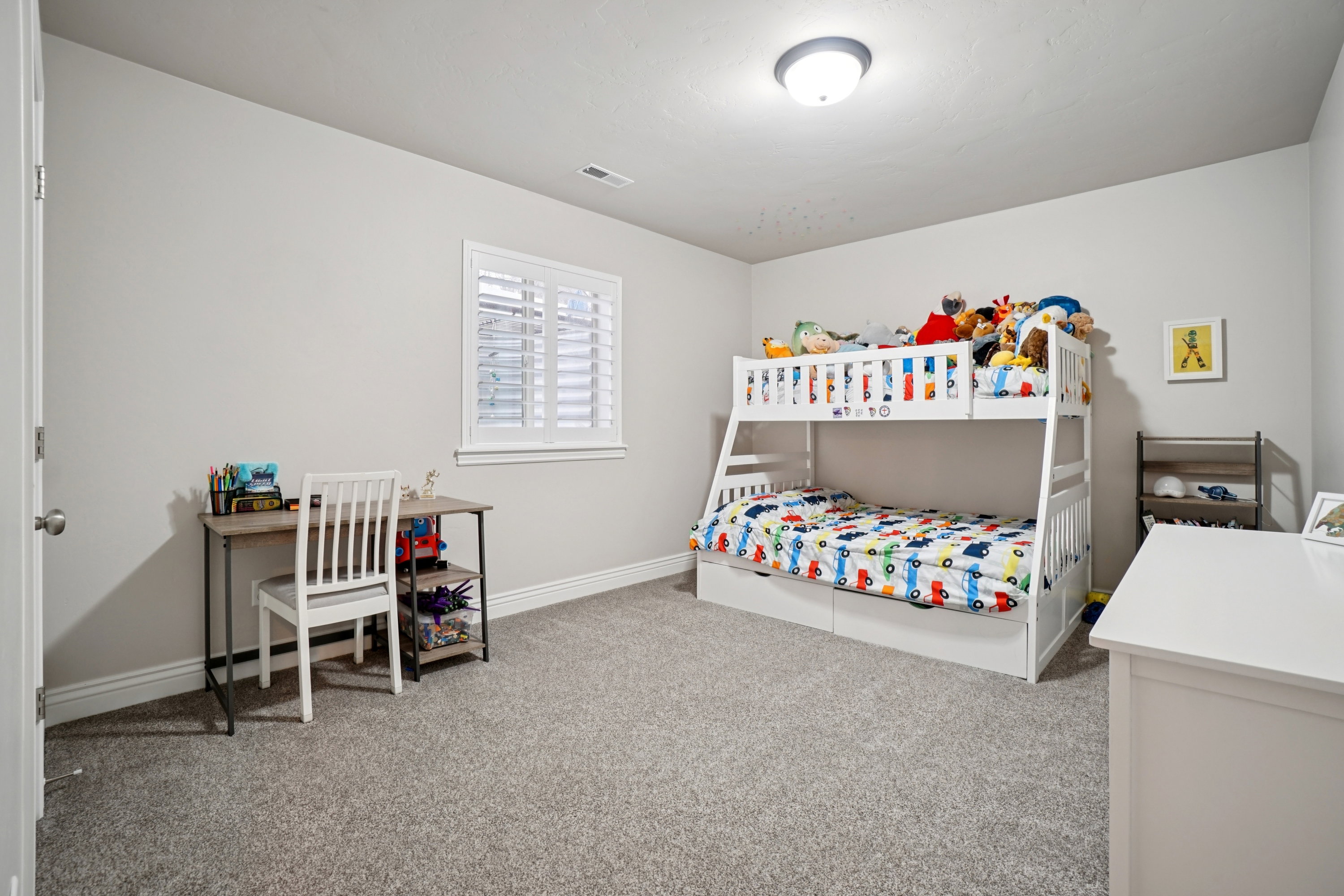 Carpeted bedroom featuring neutral wall tones, a single window with plantation shutters, white baseboards, and a flush-mount ceiling light fixture