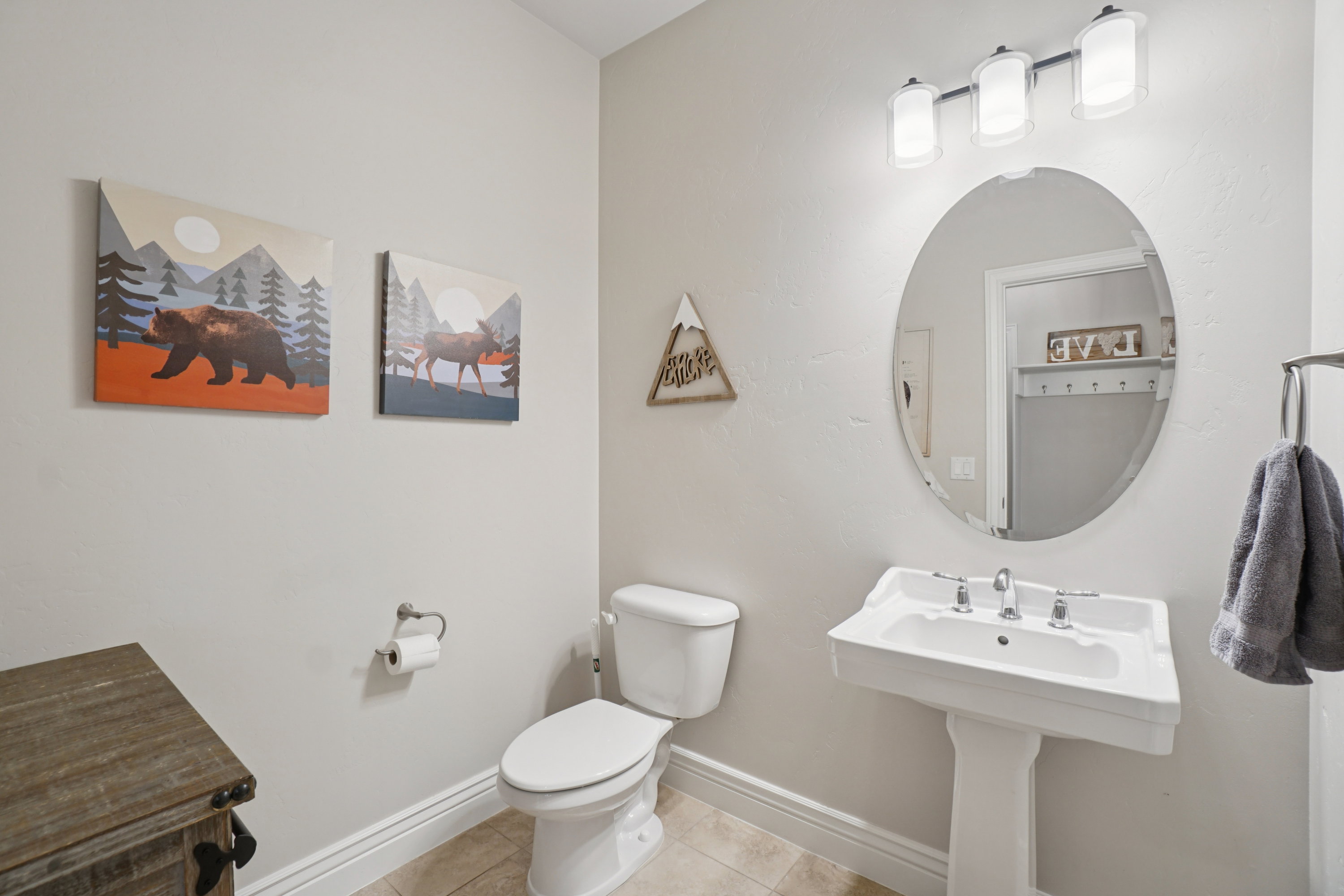 Pedestal sink with a three-light vanity fixture and oval mirror