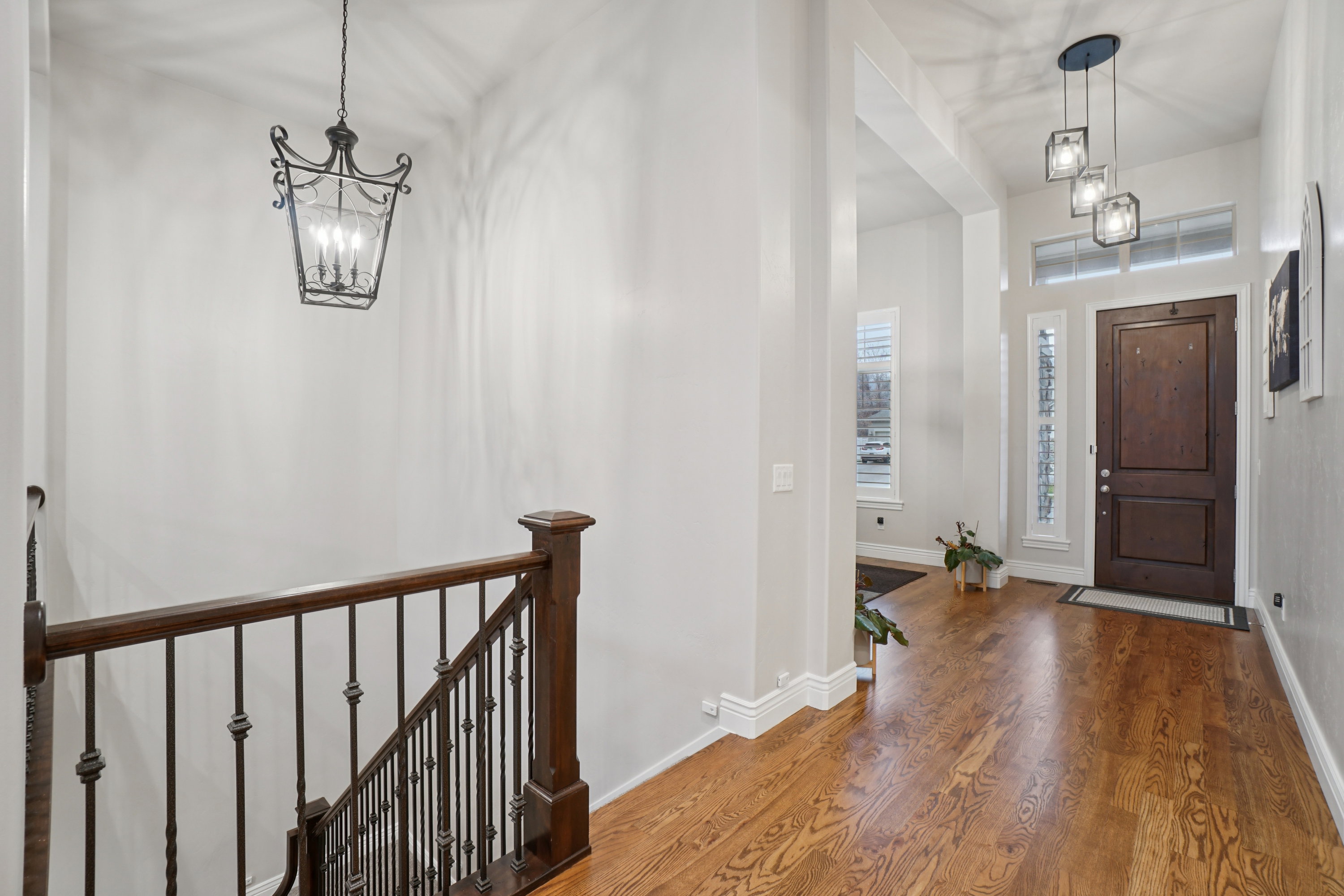 Foyer featuring wood-finish flooring, a dark wood entry door with side light, and a multi-pendant cube chandelier