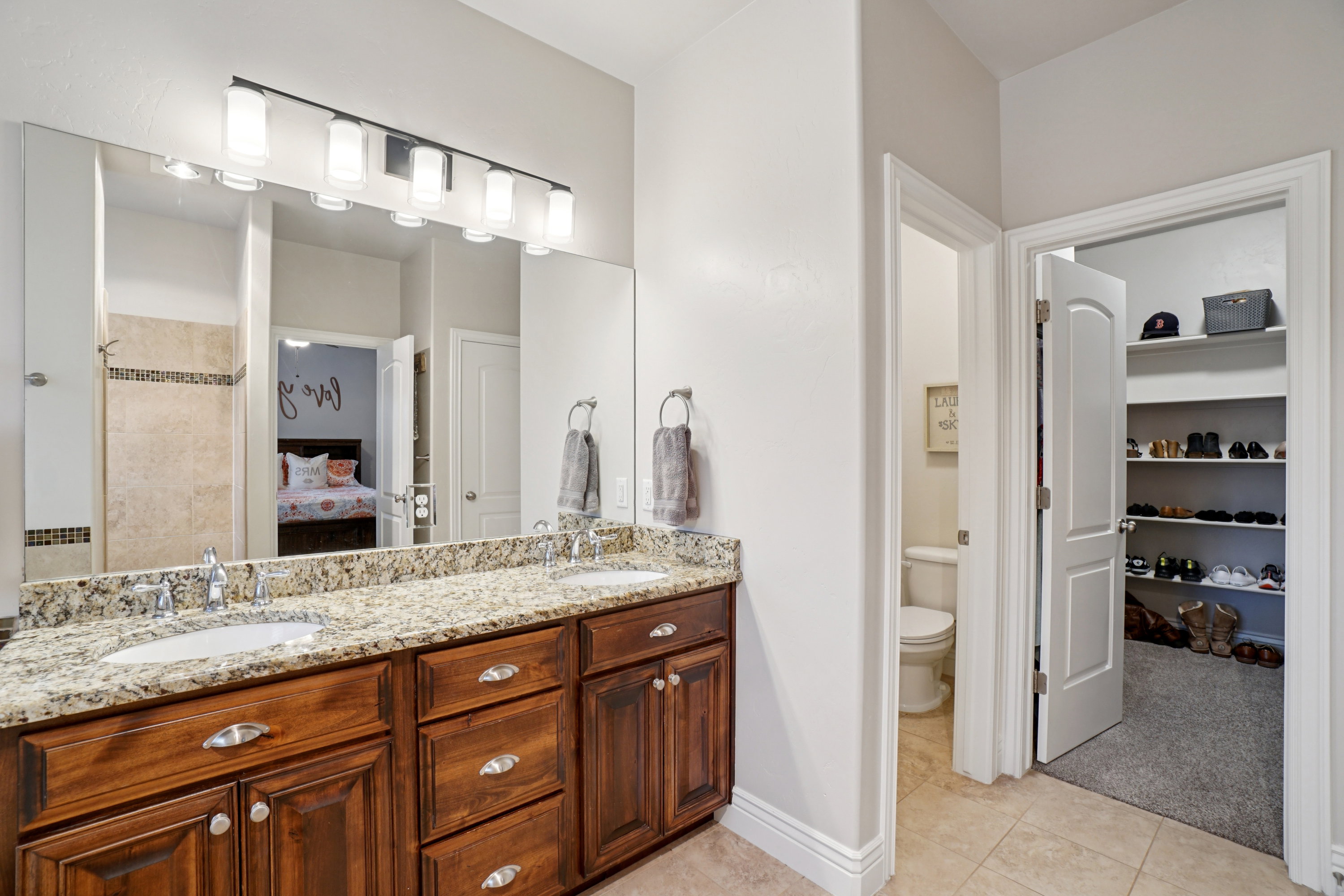 Bathroom featuring a dual vanity with a granite countertop, undermount sinks, and wood cabinetry
