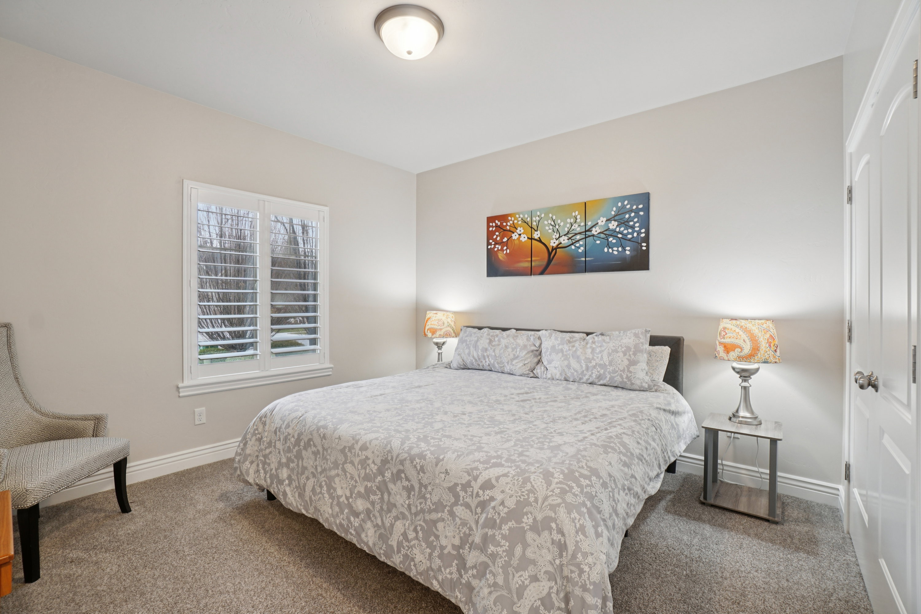 Bedroom featuring neutral wall paint, gray carpeting, a built-in window with plantation shutters, white trim, and a white interior door