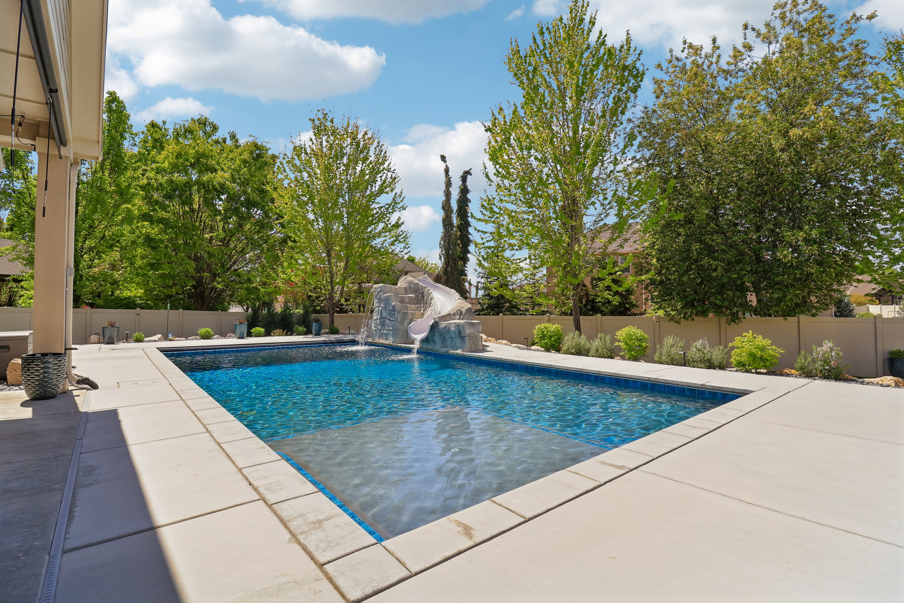 Rectangular swimming pool featuring a rock-formation slide and waterfall