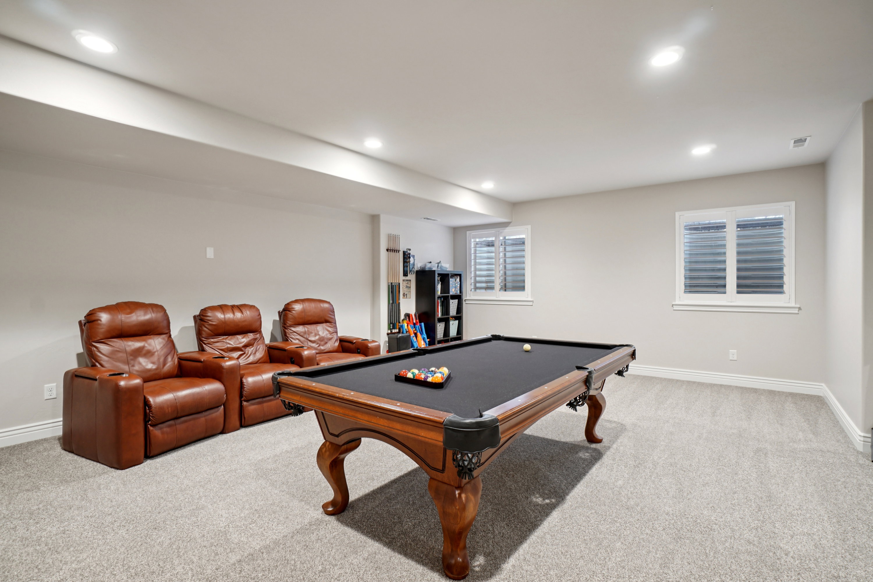 Spacious entertainment area featuring light gray carpeting and recessed lighting