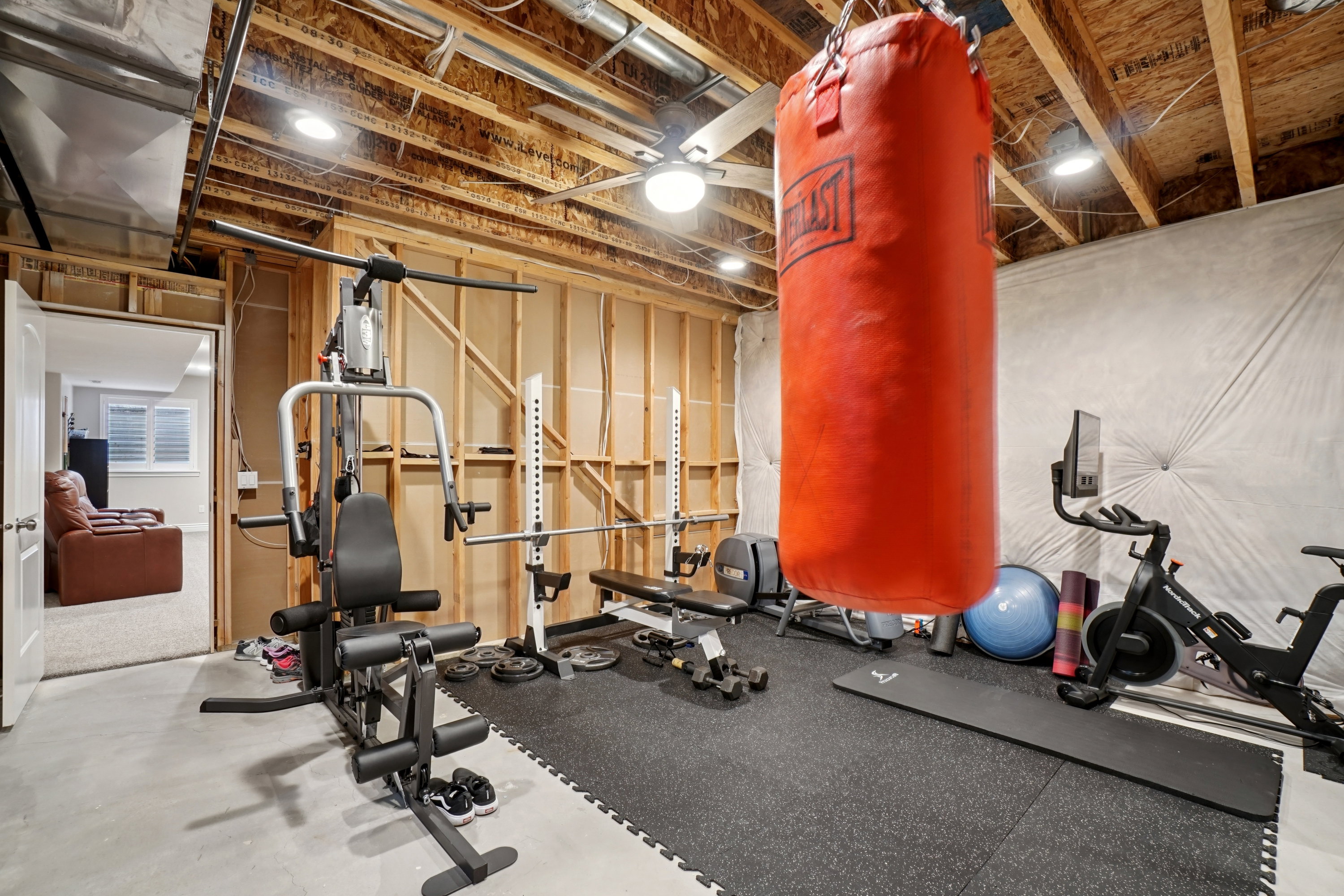 Versatile unfinished basement space featuring exposed wood framing, concrete flooring, recessed lighting, and a ceiling fan