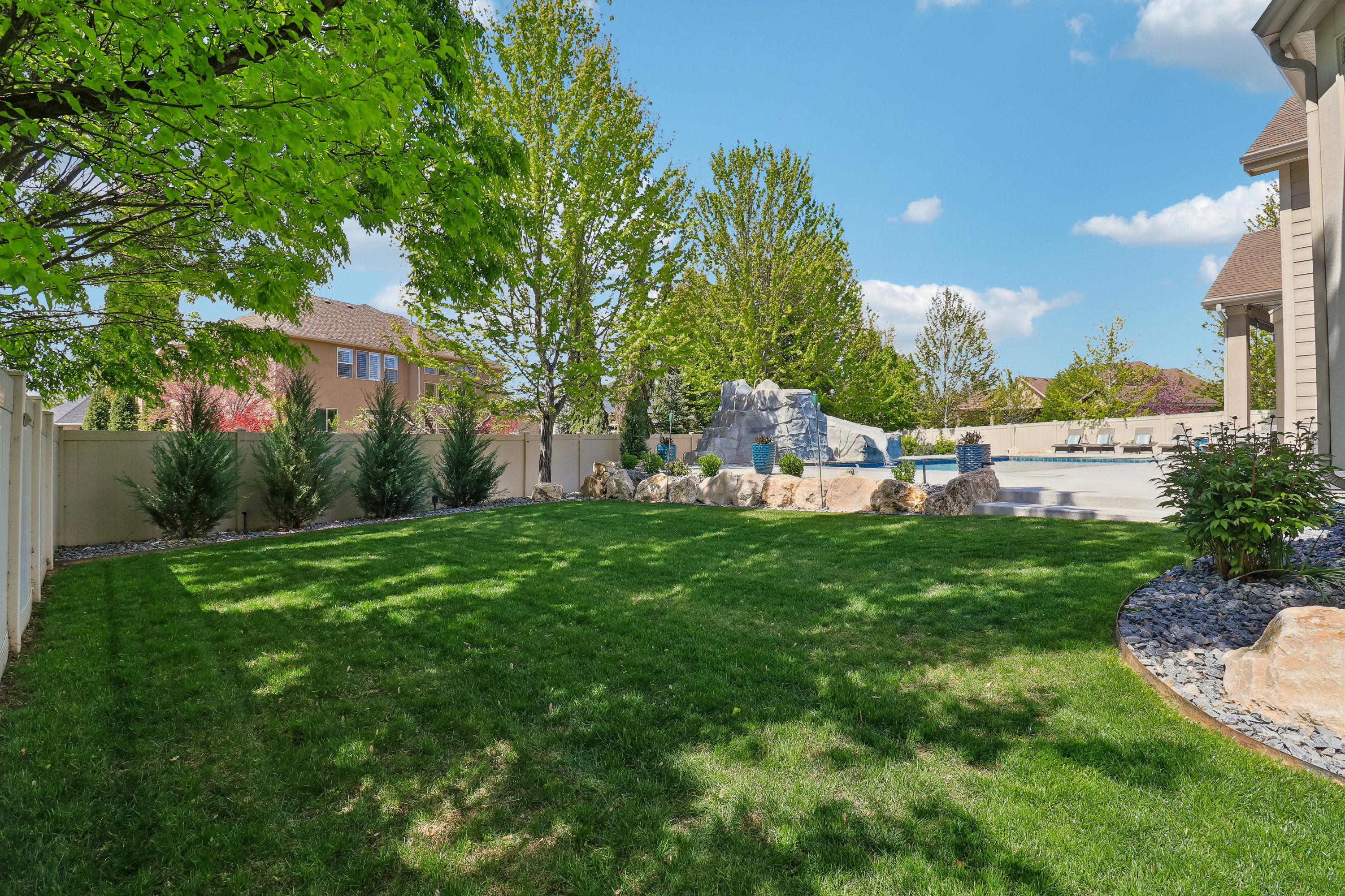 Expansive lawn area featuring a decorative rock border and mature plantings