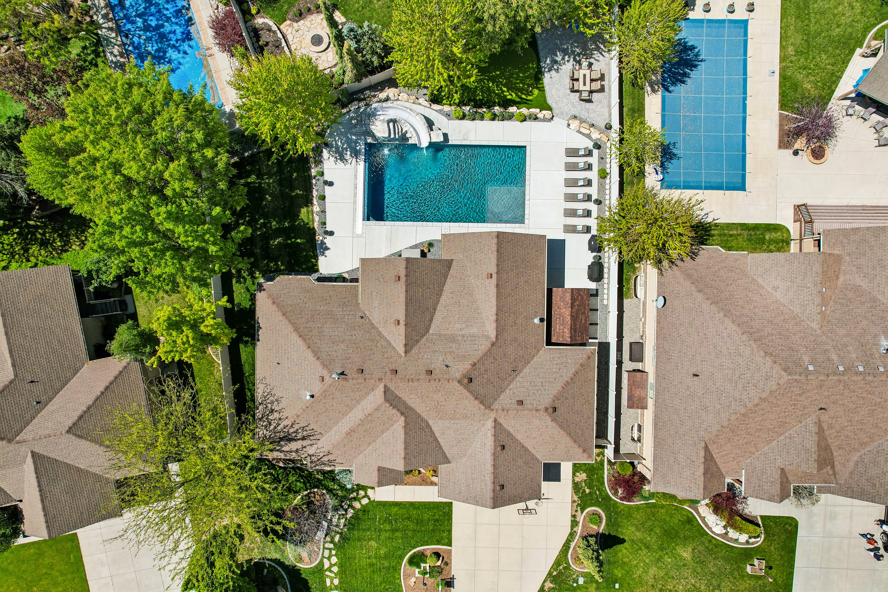 Expansive property featuring a large main residence with a complex roofline, a private swimming pool with a white concrete surround, and a manicured green lawn