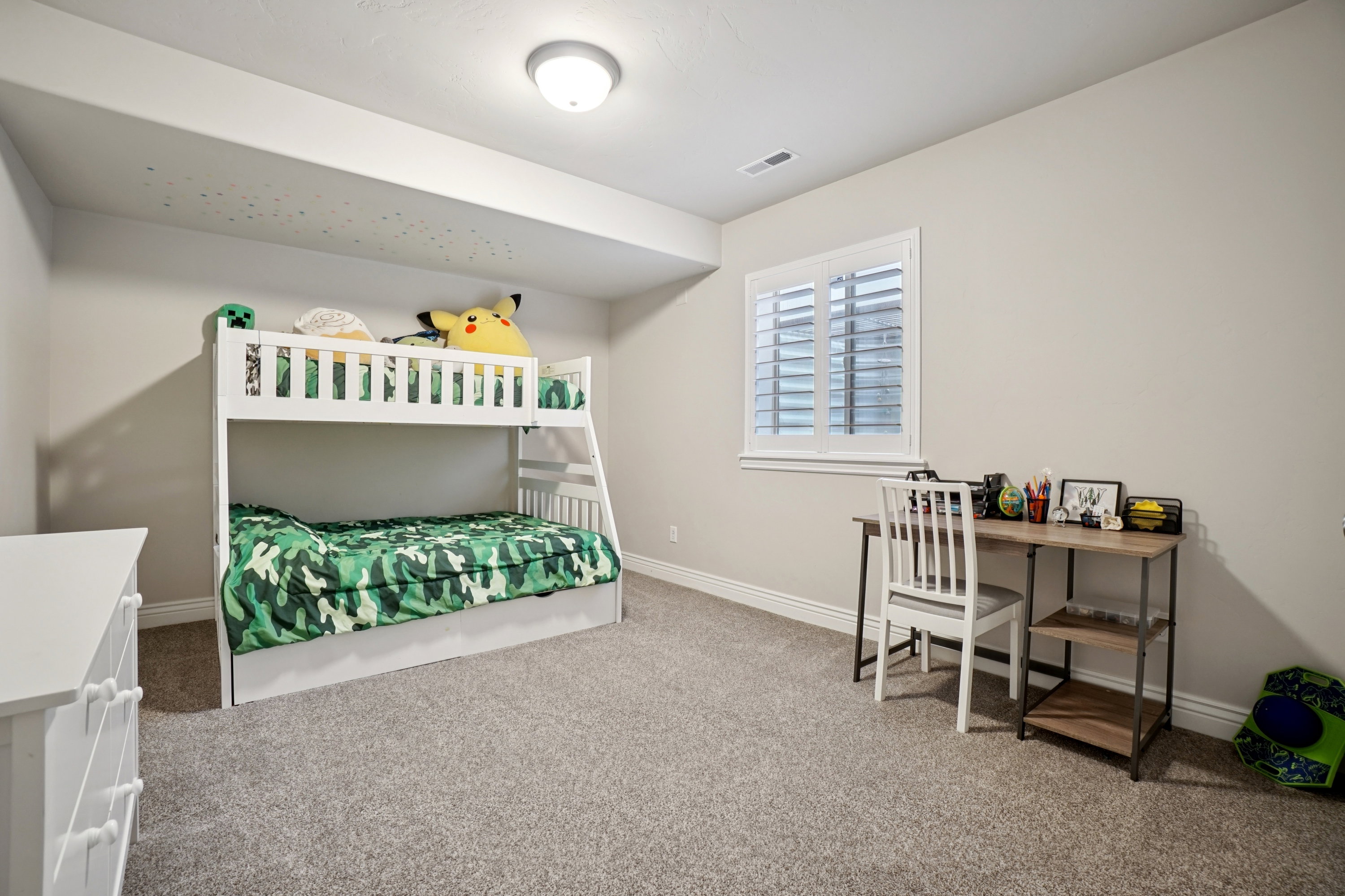 Spacious room with plush gray carpeting, neutral wall tones, and white plantation shutters on the window