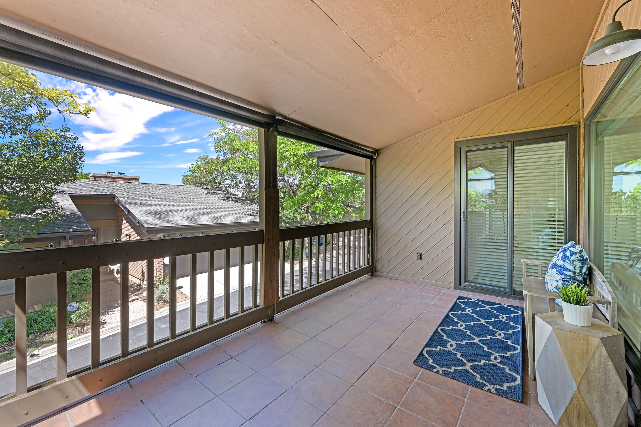 Covered balcony featuring tile flooring and a wooden railing
