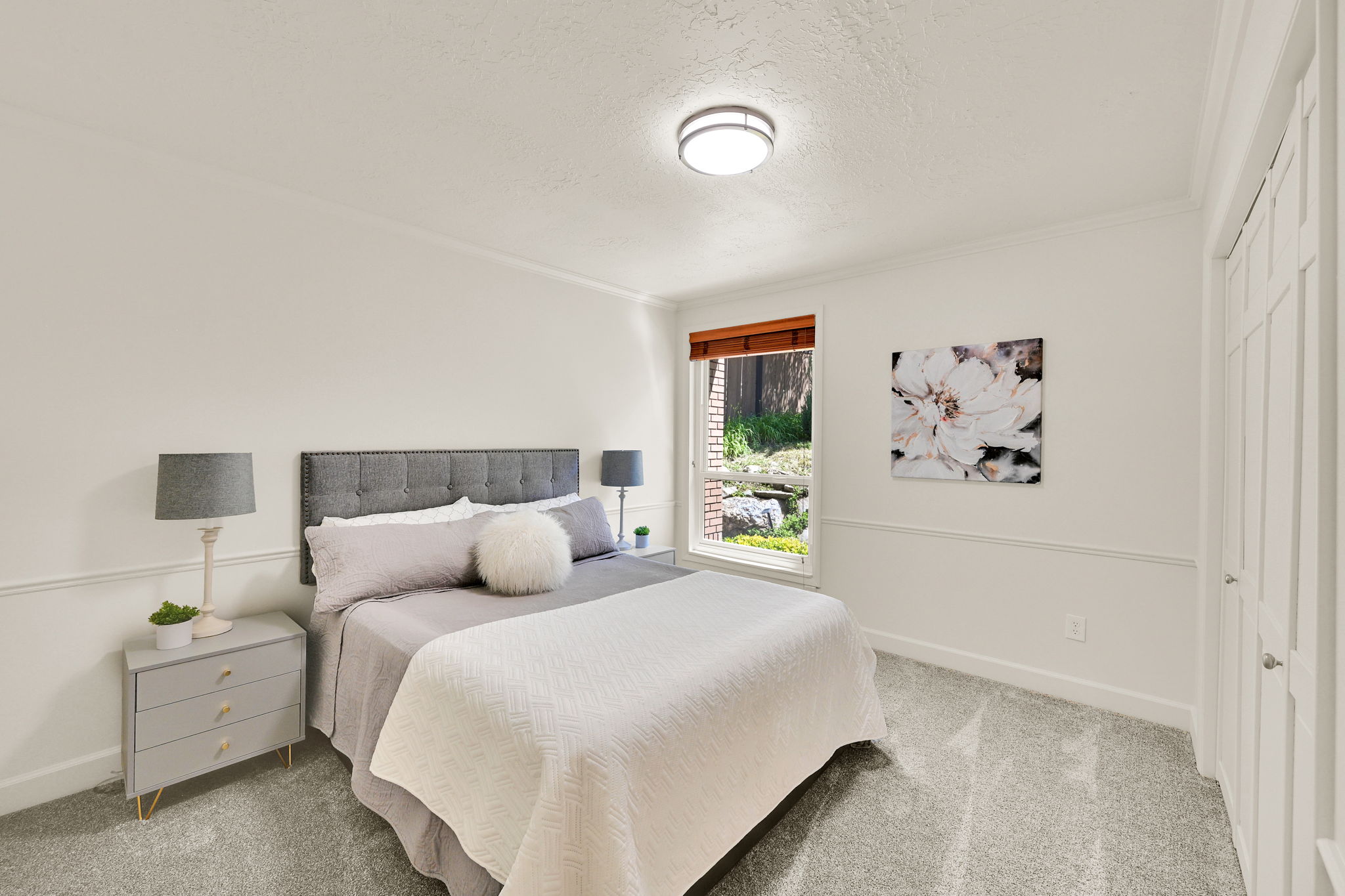 Bedroom featuring light gray carpet flooring and white walls with wainscoting