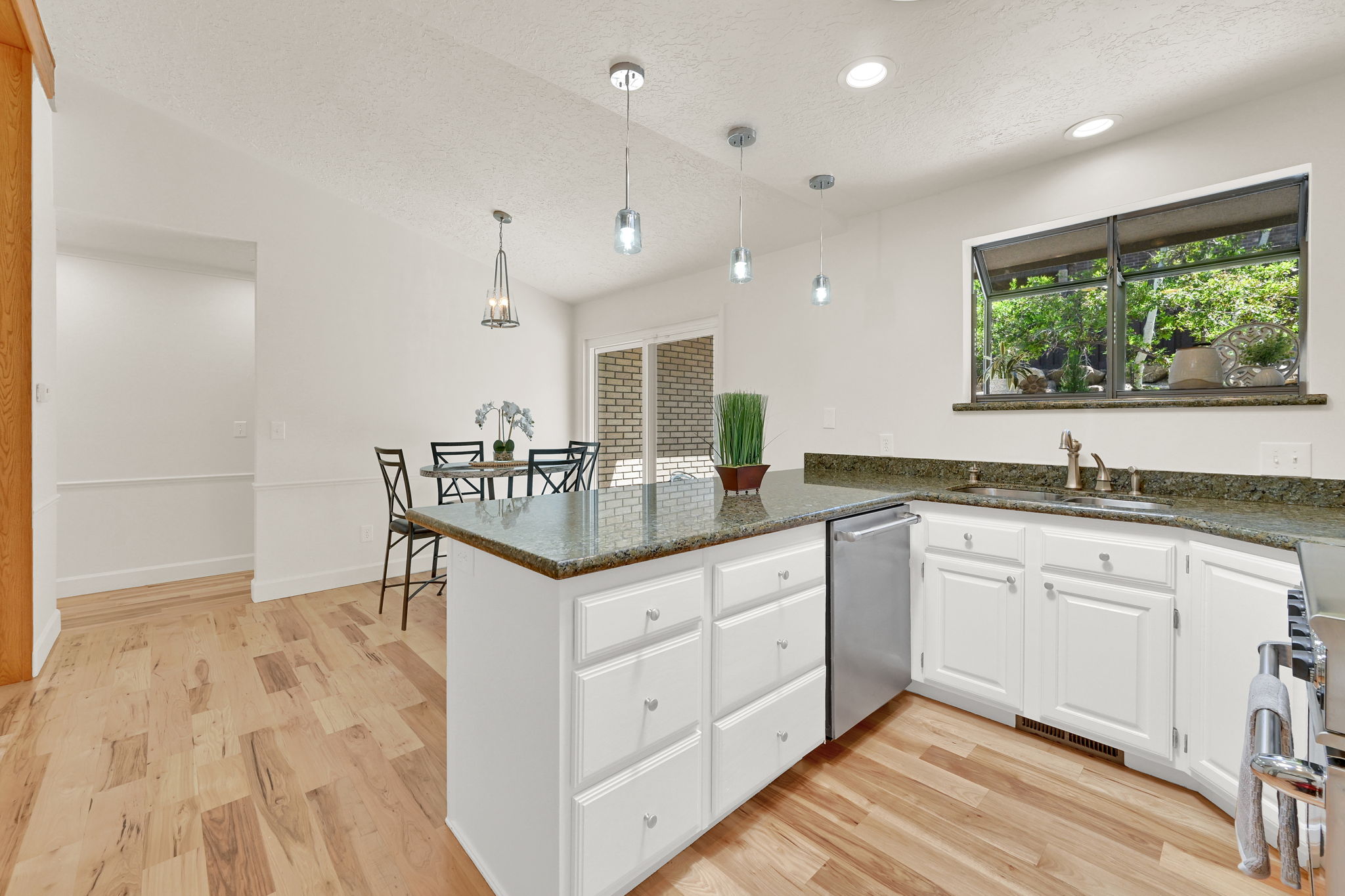 Kitchen with wood-finish flooring, white cabinetry, and granite countertops