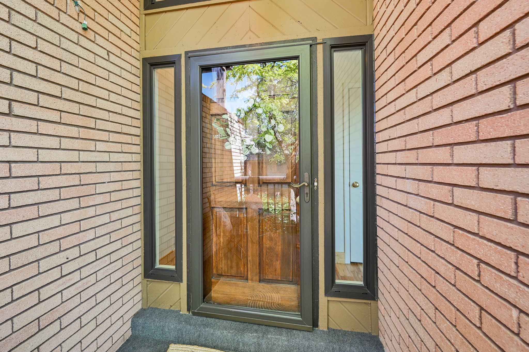 Entryway featuring a wood-finish door with a full-view storm door, flanked by narrow sidelight windows