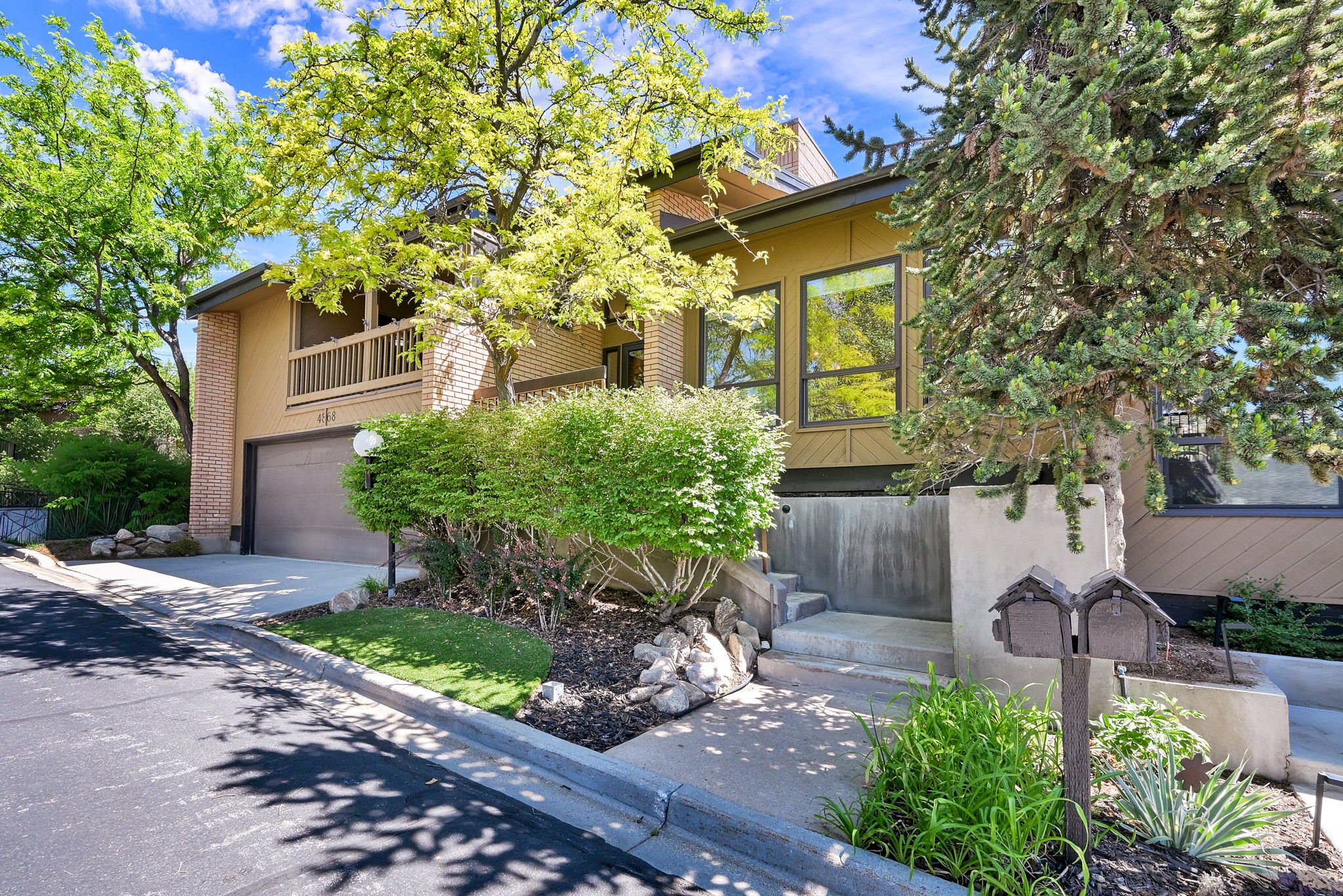 Contemporary exterior featuring a warm earth-tone facade, brick accents, and a two-car garage