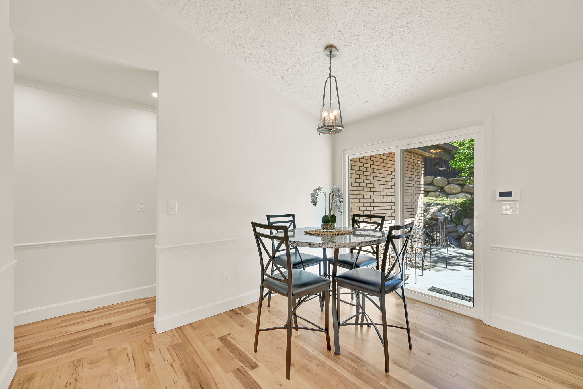Room featuring wood-finish flooring, white walls with chair rail molding, and a contemporary chandelier