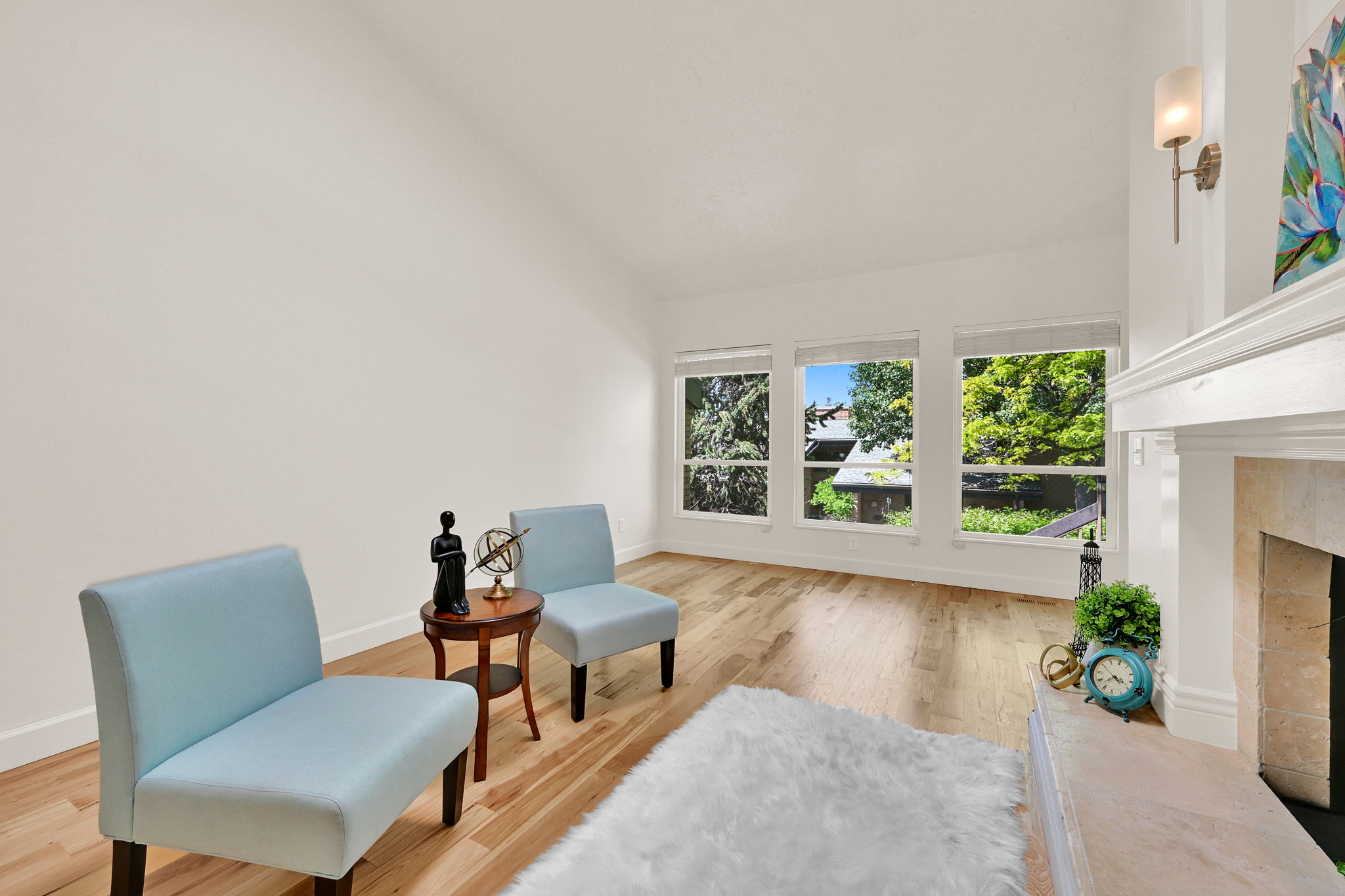 Living area featuring wood-finish flooring, a white mantel, and a sconce light fixture