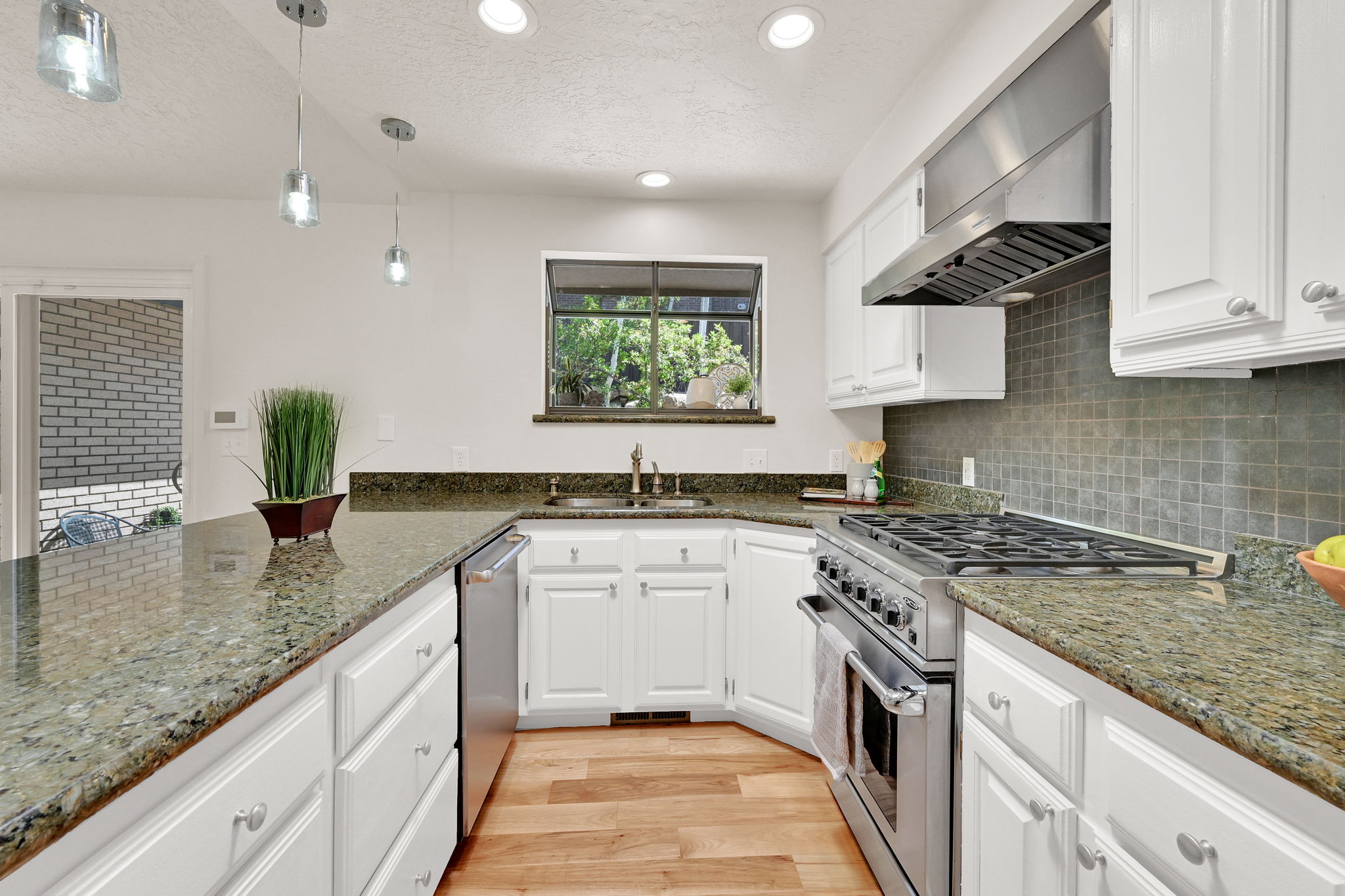 Kitchen featuring wood-finish flooring, white cabinetry, and granite countertops