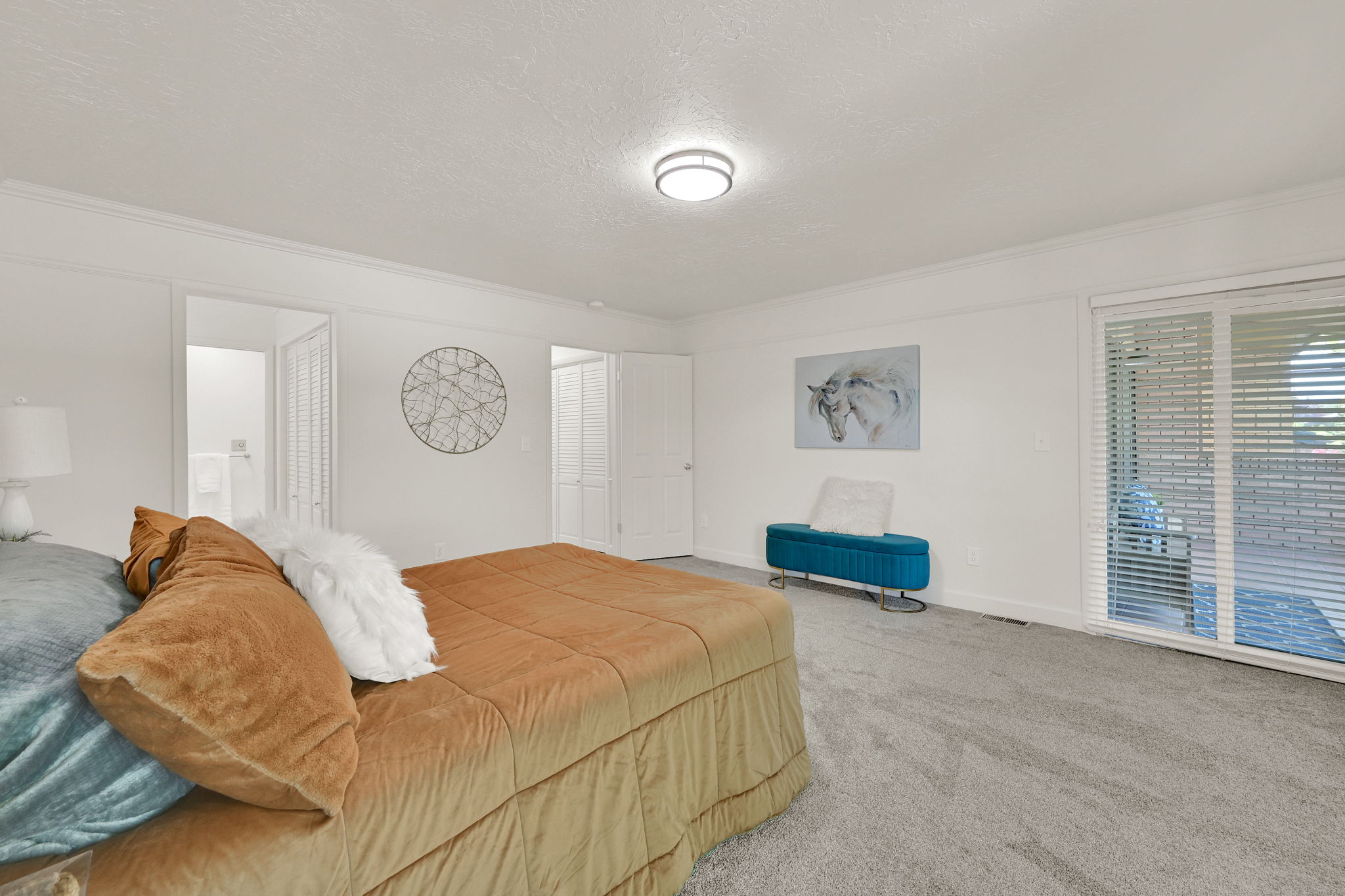 Spacious bedroom featuring light gray carpeting, crisp white walls, and crown molding