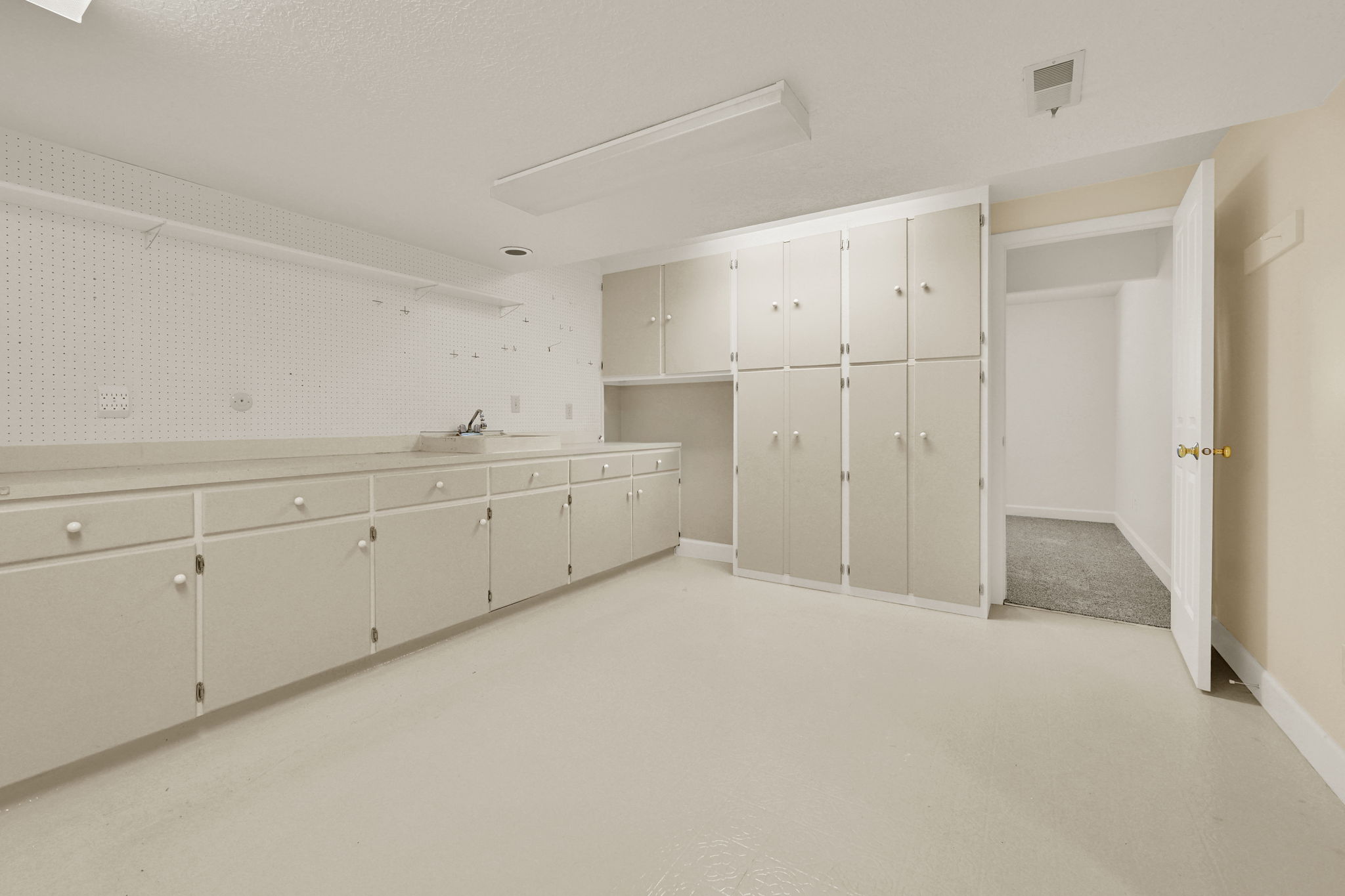 Utility room featuring extensive built-in cabinetry, long countertops, and an integrated sink