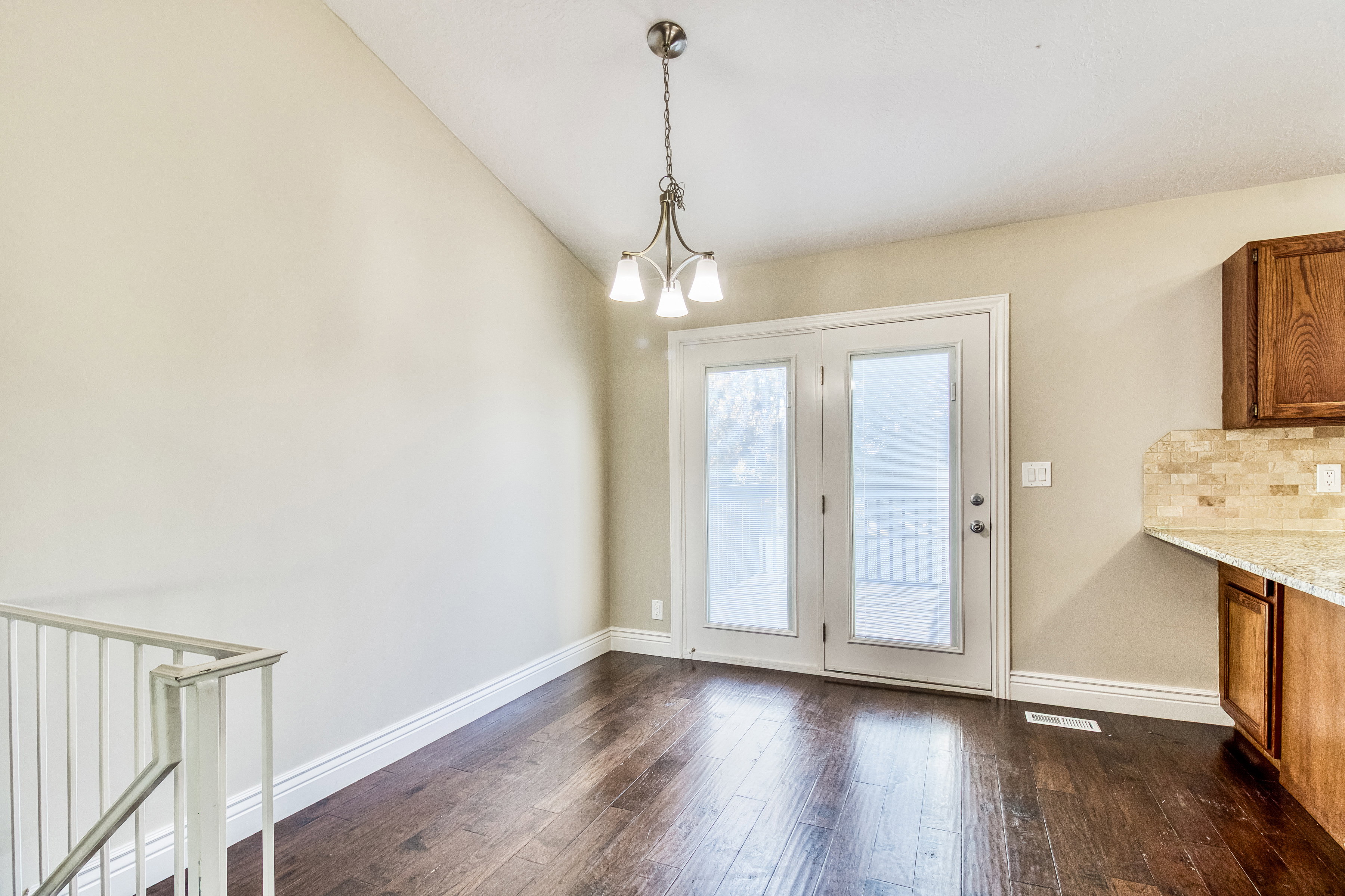 Dining area featuring vaulted ceilings, dark wood-finish flooring, white baseboards, and a contemporary chandelier