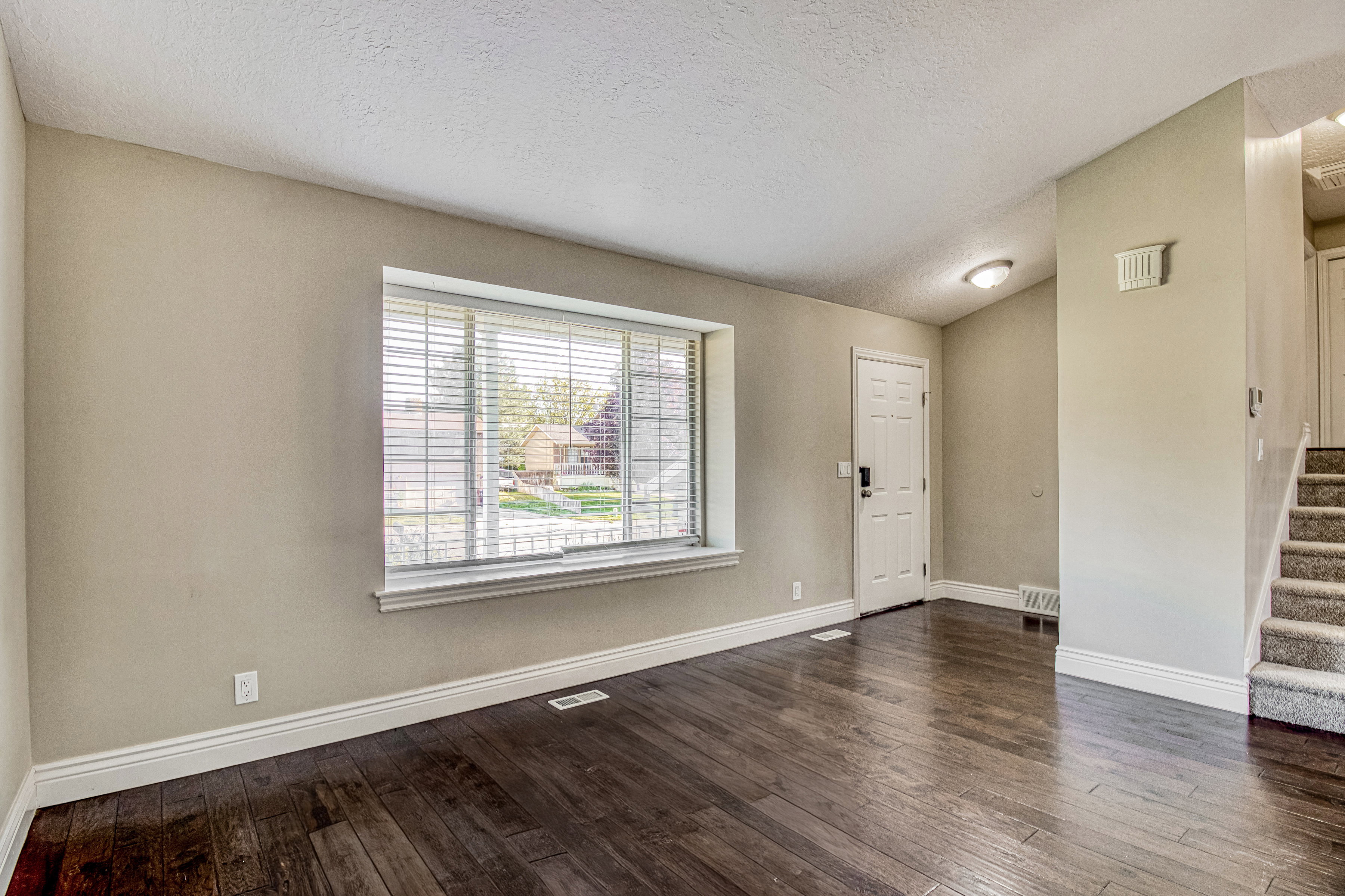 Living space featuring dark wood-finish flooring, light neutral-toned walls, and white baseboards