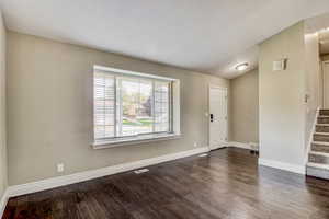 Living space featuring dark wood-finish flooring, light neutral-toned walls, and white baseboards