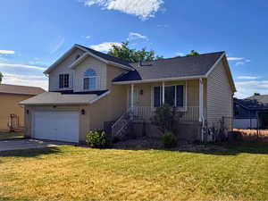 Brick and siding exterior featuring a covered front porch with white railing, an attached two-car garage, and a peaked roofline