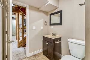 Bathroom featuring a dark wood-finish vanity with an integrated sink, framed mirror, and tile flooring