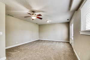 Spacious room featuring neutral carpeting, light-toned walls, and white baseboards