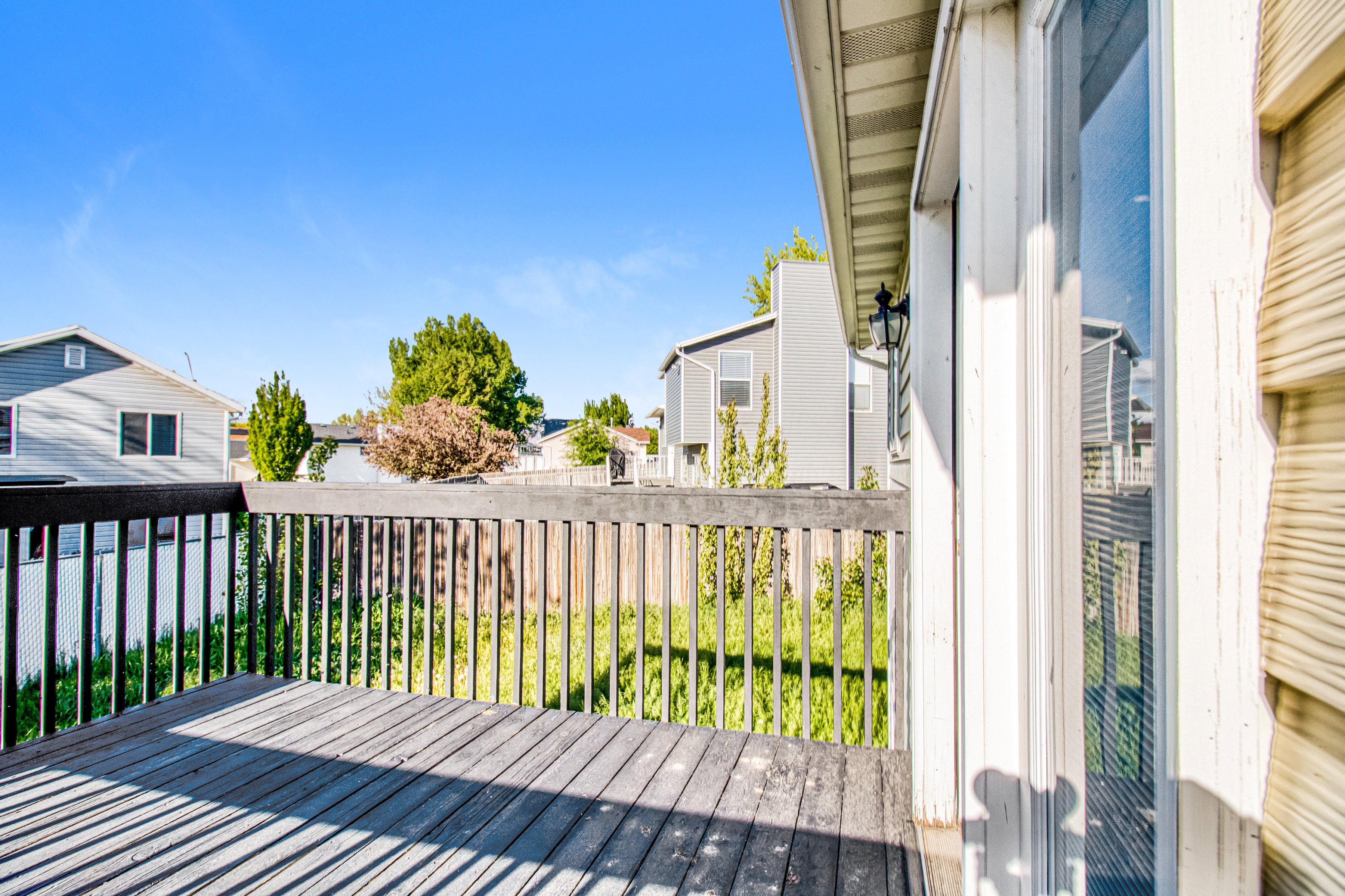 Outdoor deck featuring wood-finish decking, dark wood railing, and a sliding glass door with white trim