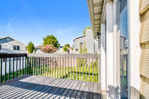 Outdoor deck featuring wood-finish decking, dark wood railing, and a sliding glass door with white trim