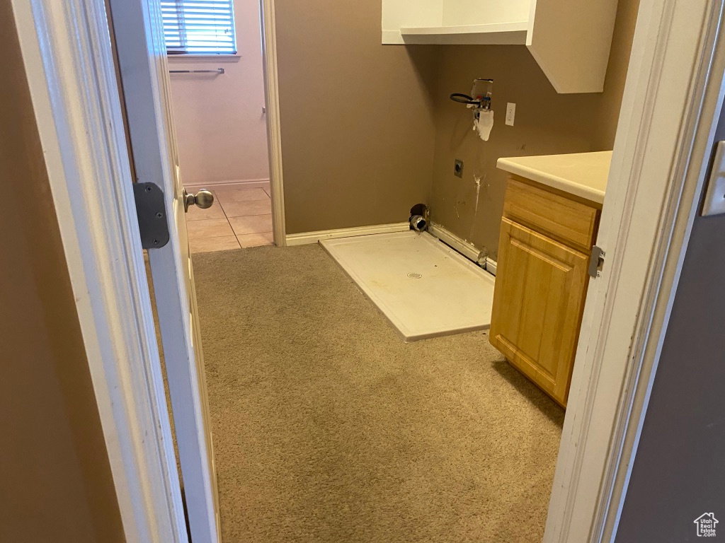 Utility area with carpeted flooring, a light wood-finish base cabinet, and a white countertop