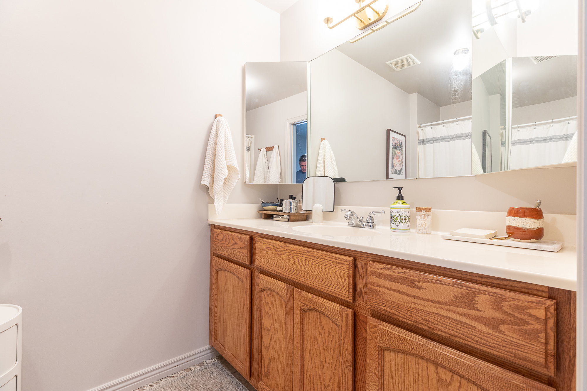 Bathroom vanity featuring wood cabinetry, a white countertop, and a built-in sink with a chrome faucet