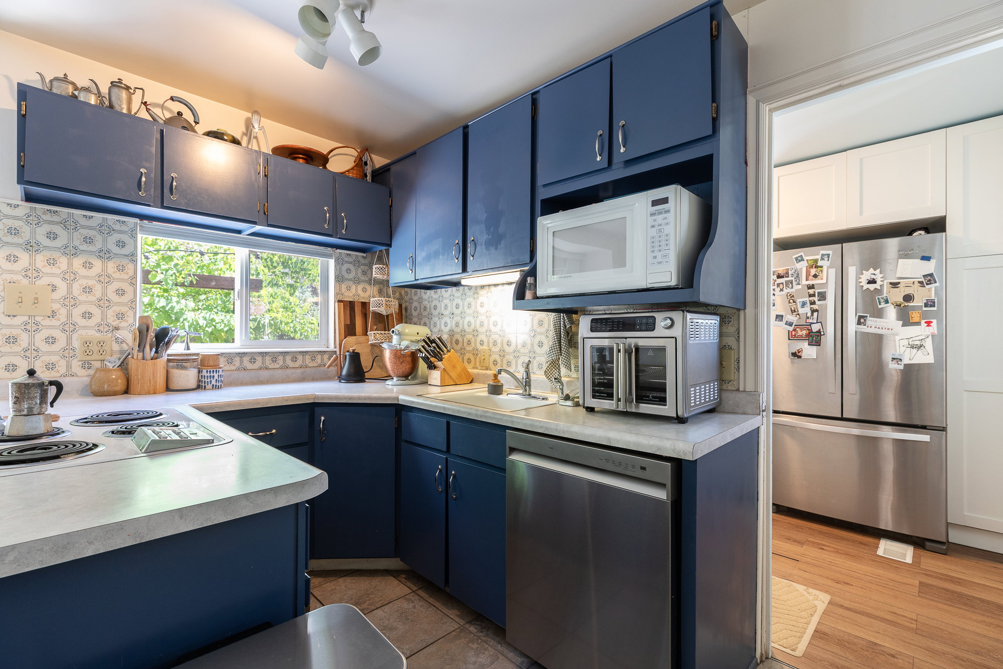 Kitchen featuring blue cabinetry, white countertops, ceramic tile backsplash, and a built-in dishwasher