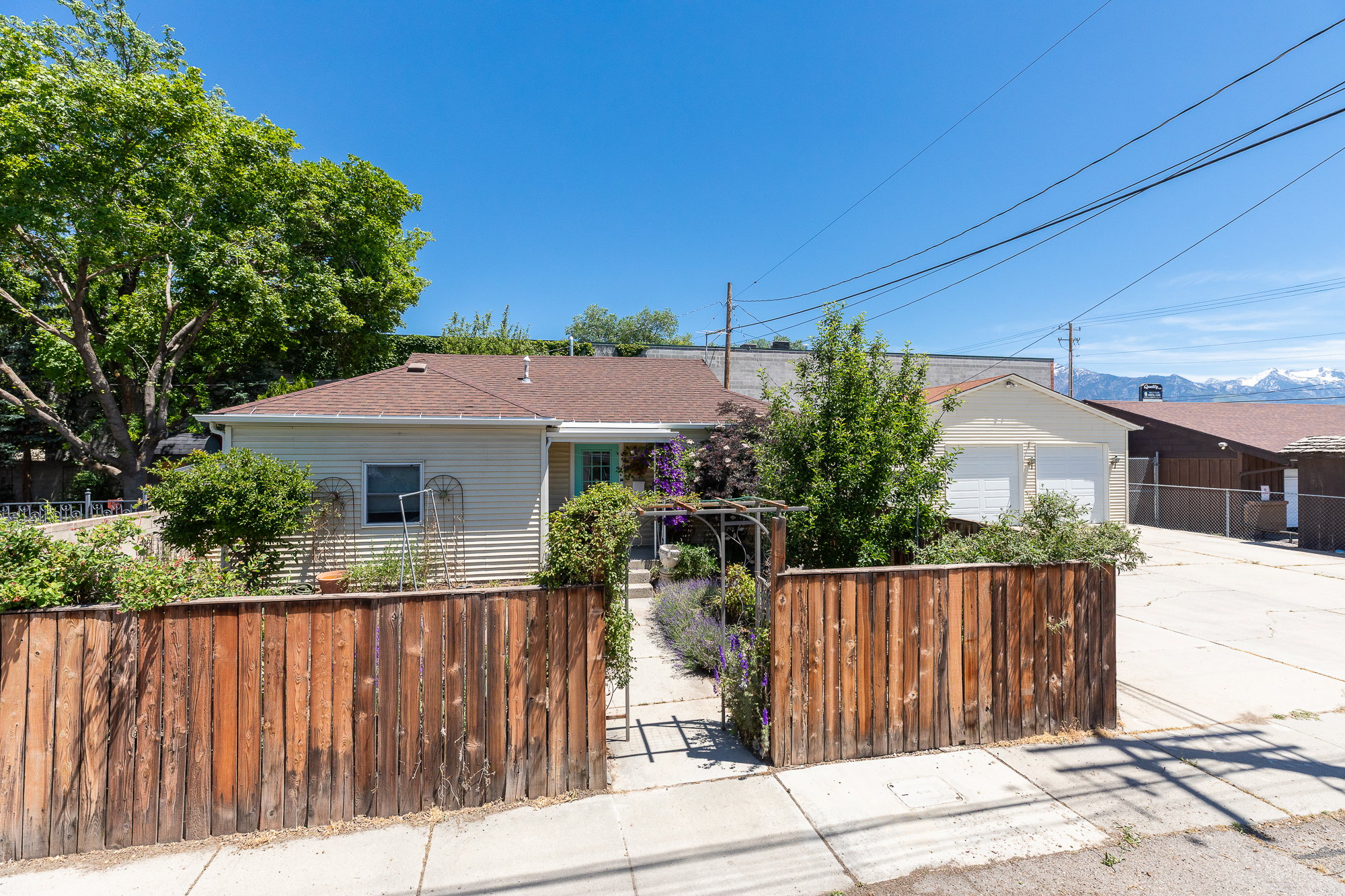 Front yard featuring a wooden privacy fence, a paved walkway, and mature landscaping