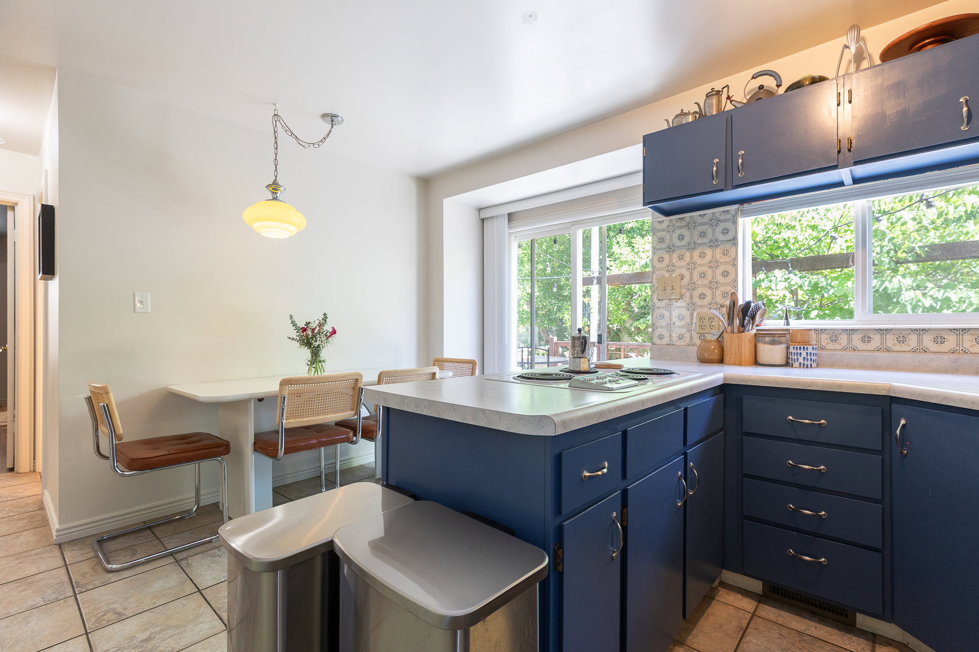 Kitchen featuring blue cabinetry with silver-tone hardware, a white countertop, and patterned tile backsplash