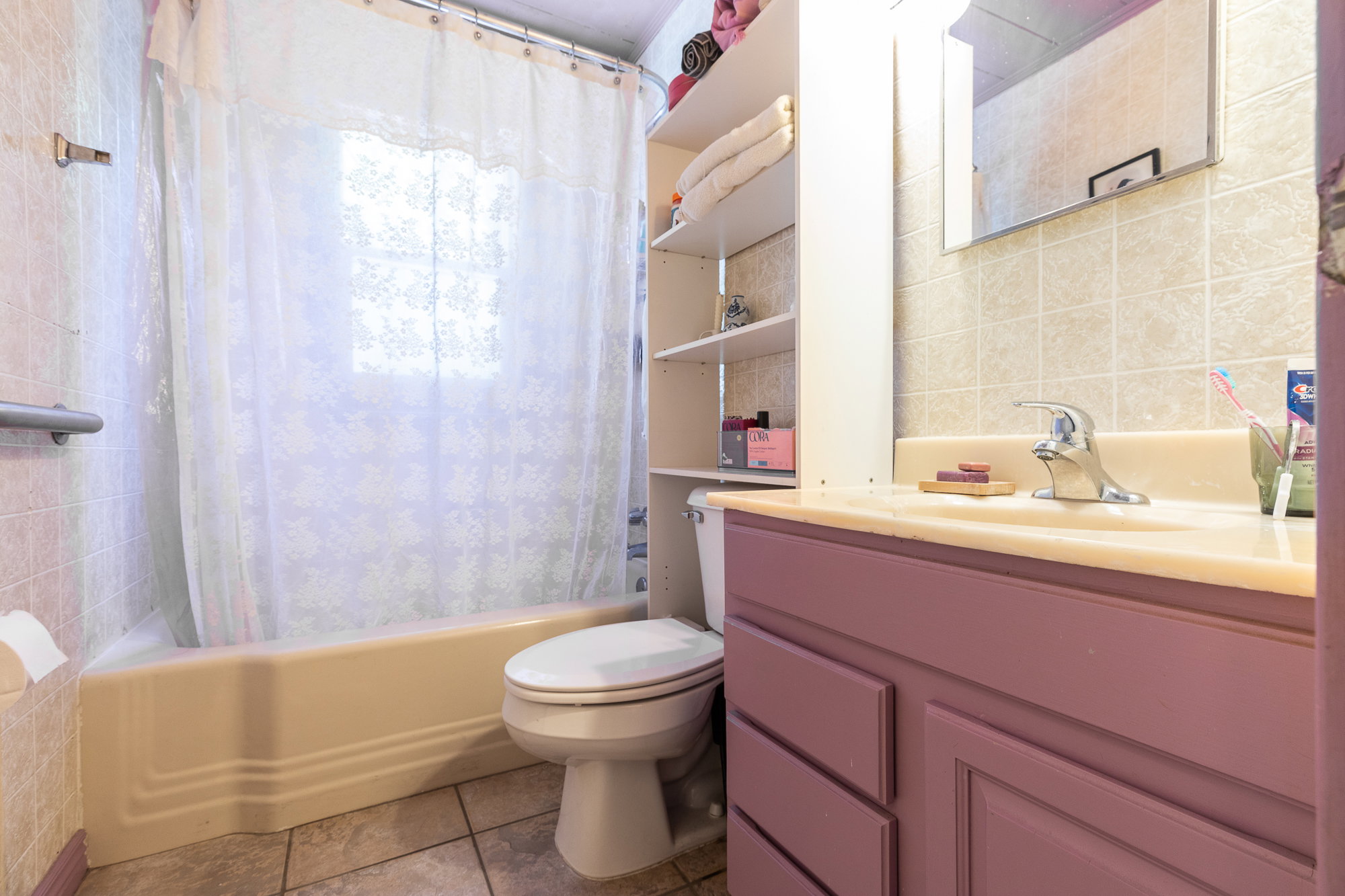 Bathroom featuring a bathtub, toilet, vanity with a built-in sink, and wall-mounted shelving