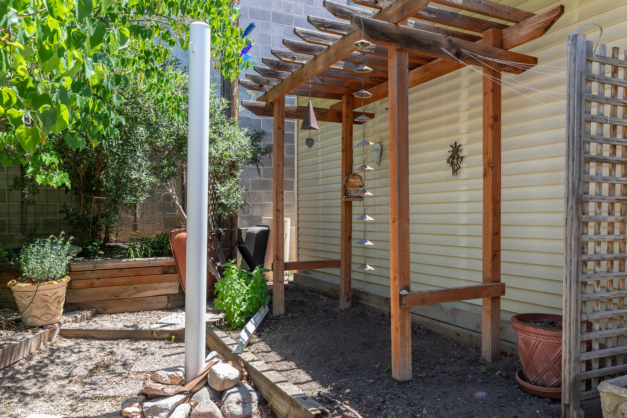Wood pergola structure alongside a home with horizontal siding