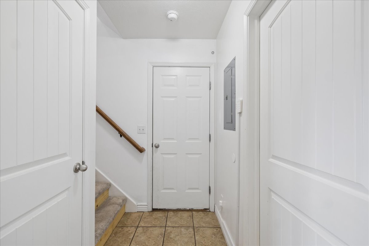 Foyer featuring ceramic tile flooring, a carpeted staircase with wood handrail, and white panel doors