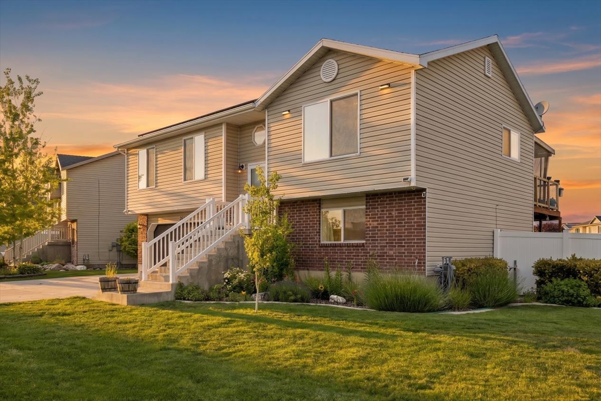 Split-level residence featuring beige horizontal siding and brick accents