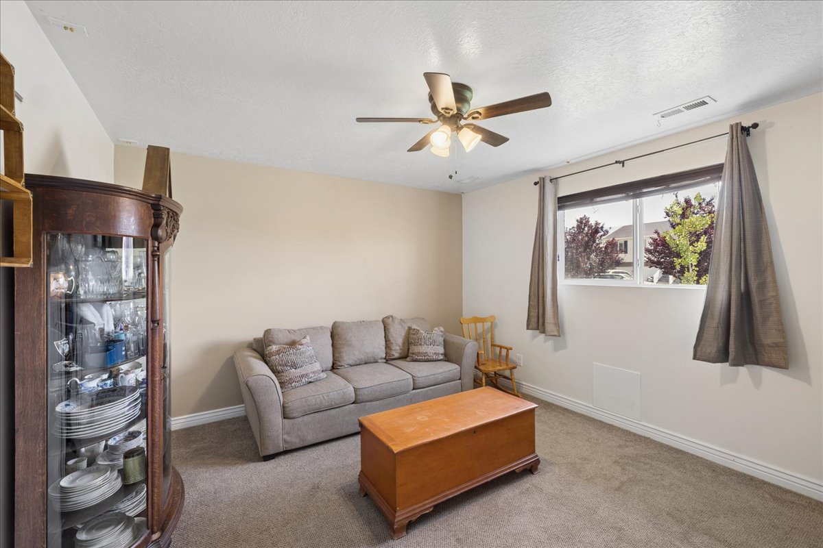 Carpeted room with neutral paint, featuring a ceiling fan with integrated lighting